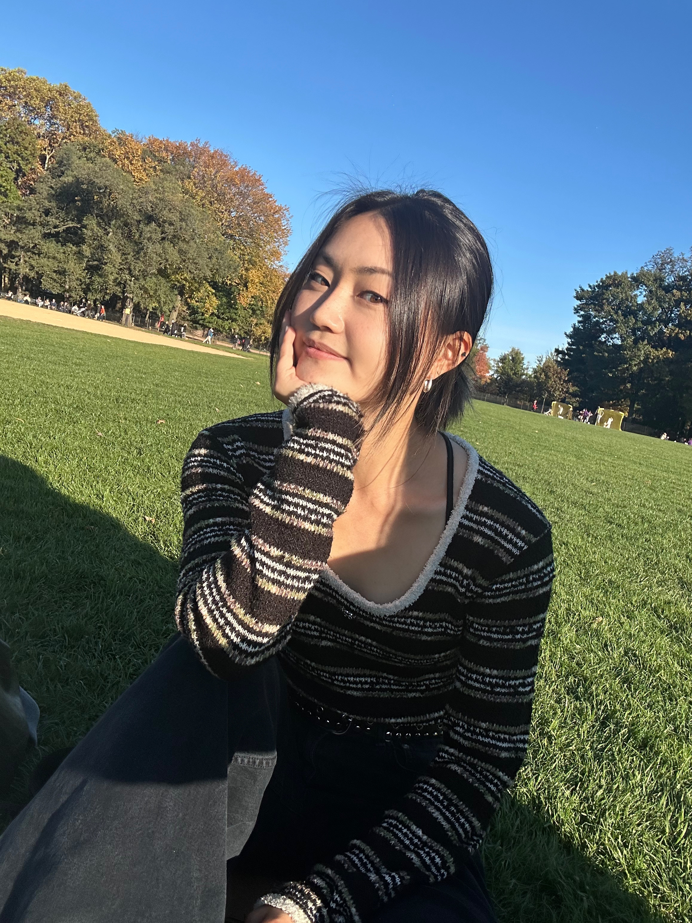June Nam sitting on the grass in Central Park